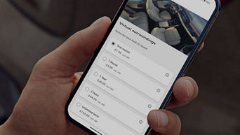 A hand holding a phone with an Audi app on screen