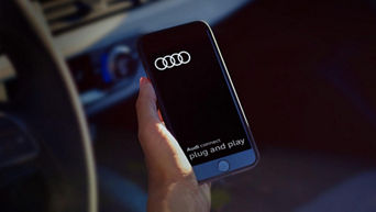 A female hand holding a phone with an Audi all launched