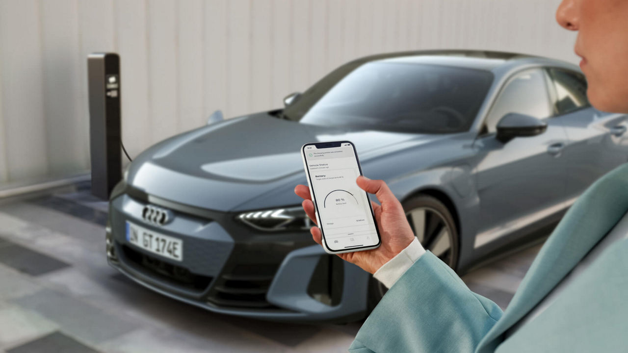 A hand holding a mobile phone with the myAudi app displayed on its screen