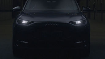 Black Audi car with LED headlights on in dark setting