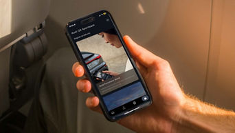 A hand holding a phone with an Audi app on screen