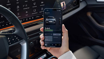 A hand holding a mobile phone with its screen the focal point displaying the myAudi app