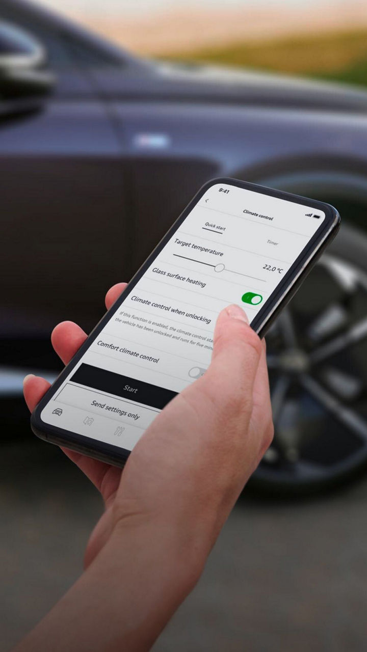 A hand holding a mobile phone with the myAudi app displayed on its screen