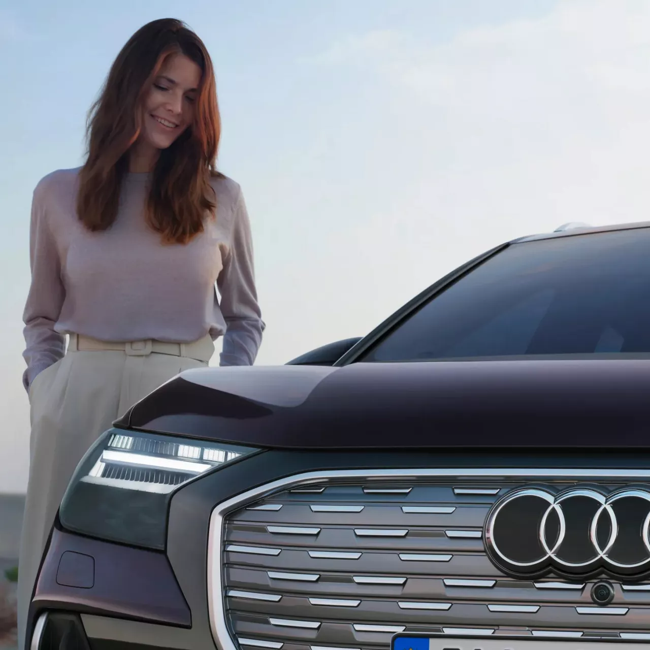 A woman stood beside the right front side of a parked Audi vehicle