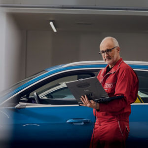 A mechanic wearing Audi overalls reading something from a computer