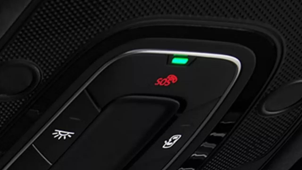 Close-up of a car control panel showing an illuminated SOS button with a red icon, and a green indicator light above it.
