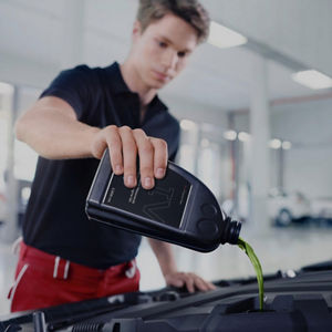 A mechanic pouring oil in a car engine part