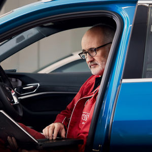 A mechanic sitting in a car while looking at a computer screen