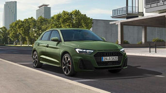 A green Audi car parked at the side of an urban street