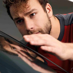 A man closely examining a car window