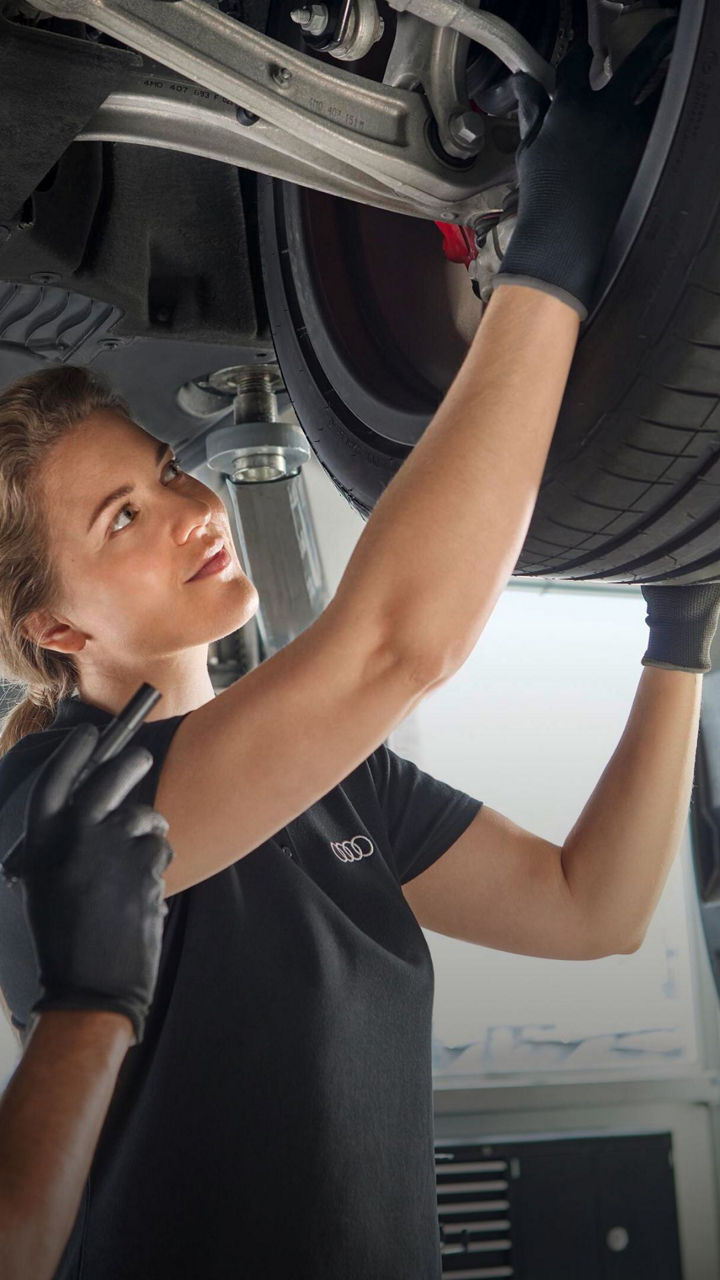 Audi mechanic inspecting the underside of an Audi around a wheel