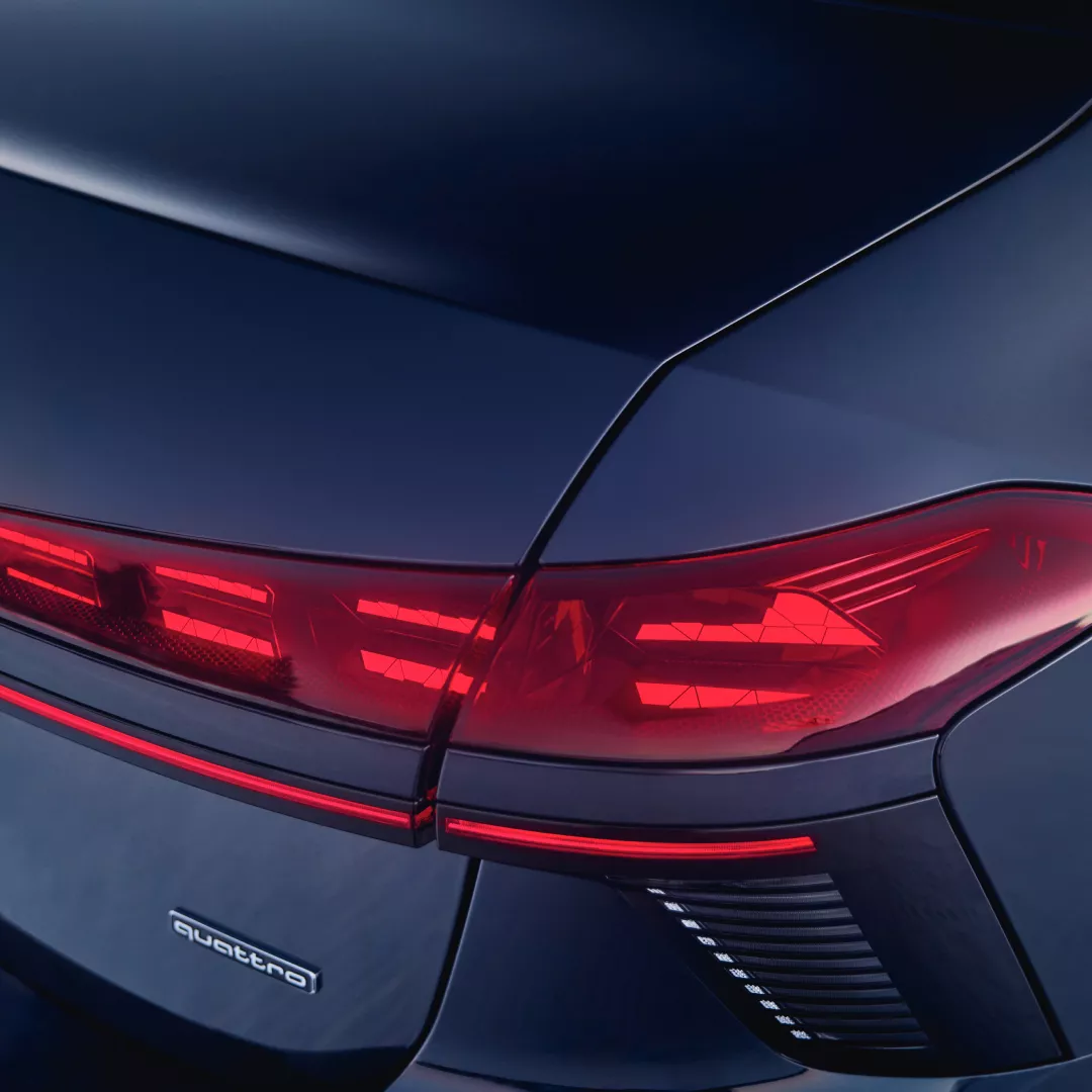 Close-up of an Audi car's sleek rear end featuring striking red taillights and the "quattro" badge.