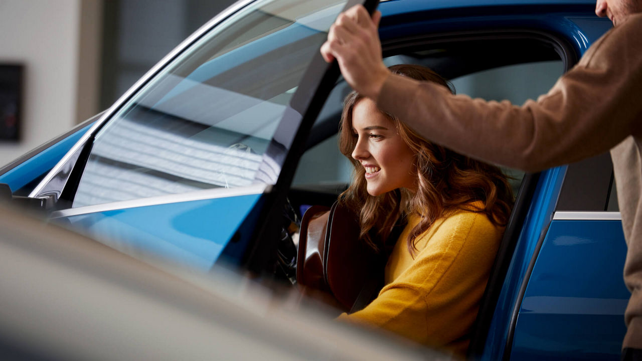 A young woman sitting in an Audi vehicle in an Audi showroom