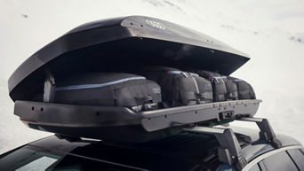 A vehicle with bags and suitcases on its roof rack that boasts an Audi logo