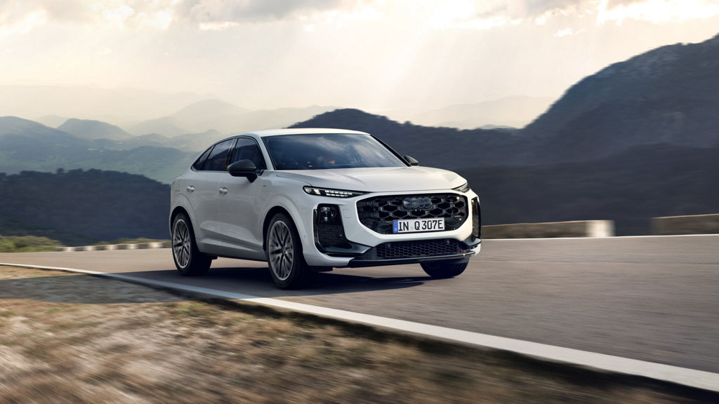 L’Audi Q3 Sportback e-hybrid sur une route de campagne. L’Audi blanche roule à grande vitesse dans un paysage montagneux.
