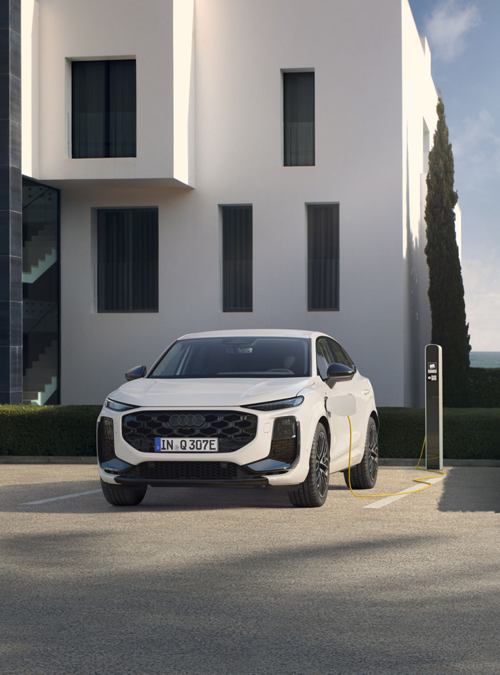 Das Bild zeigt den Audi Q3 Sportback e-hybrid. Er steht vor einem Wohngebäude mit einer Ladesäule und lädt.