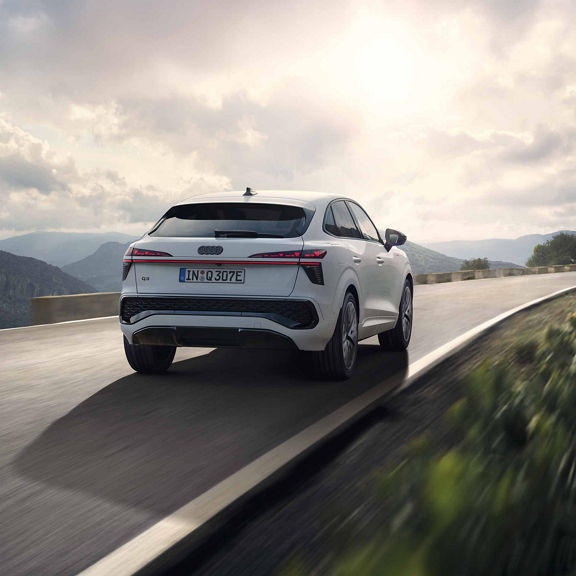 Der Audi Q3 Sportback e-hybrid fährt auf einer Landstrasse in den Bergen.