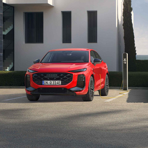 Audi Q3 Sportback e-hybrid in Rot in Seitenansicht, auf einem Parkplatz mit Ladesäule.