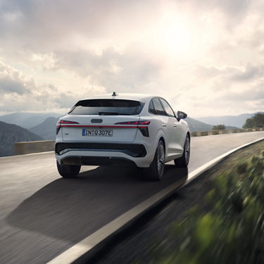 Der Audi Q3 Sportback e-hybrid fährt auf einer Landstrasse in den Bergen.