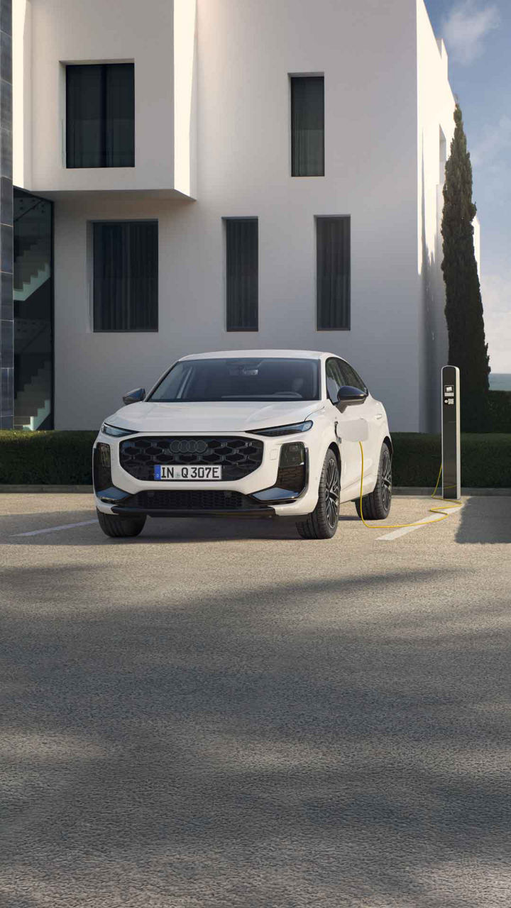 Audi Q3 Sportback e-hybrid wordt opgeladen terwijl een vrouw webloopt.