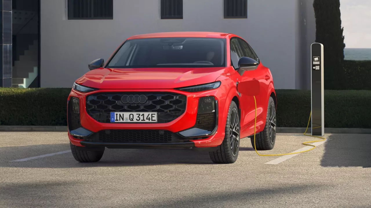 Ein roter Q3 Sportback e-hybrid parkt vor einer Ladesäule und wird mit Strom betankt.