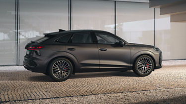 The Q3 Sportback is parked in front of the stair railing of a building on a paved path.