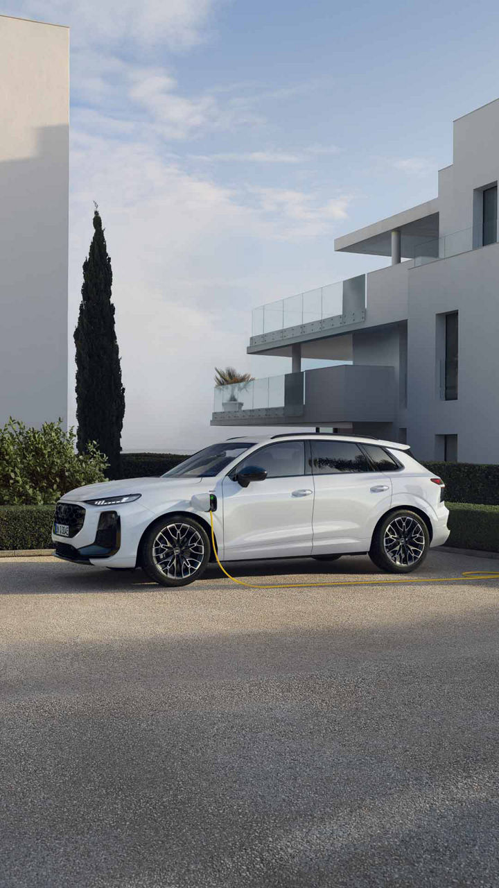 Side view of Audi Q3 SUV e-hybrid charging in a parking lot