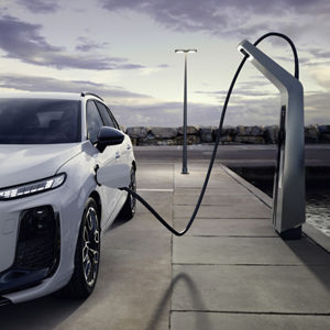 A white Q3 SUV e-hybrid at a charging station in an empty parking lot.