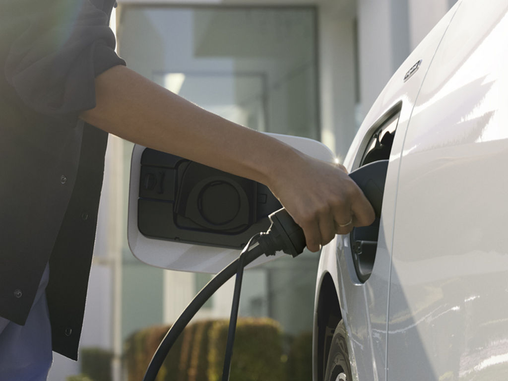 Close-up of a person connecting the charging cable to the Q3 SUV e-hybrid.	