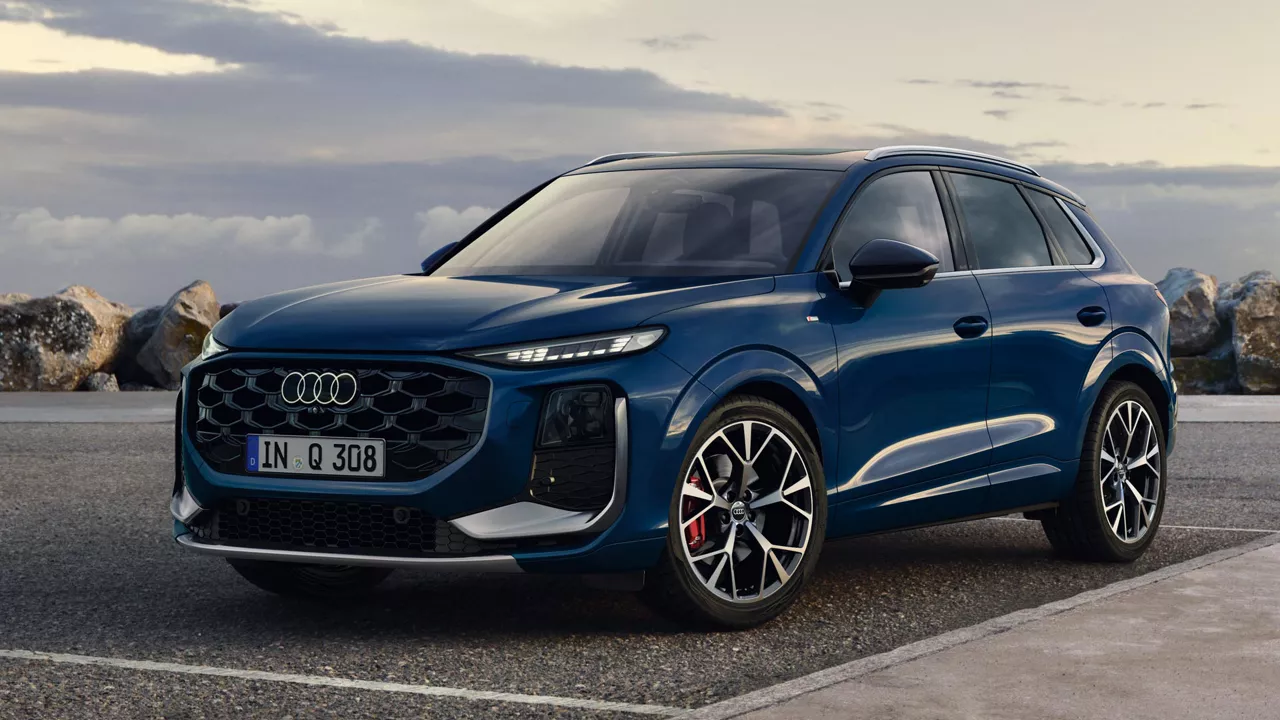 Der Q3 SUV in ascariblau metallic in seitlich, vorderer Ansicht an einer Küstenstraße parkend.