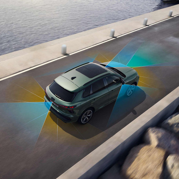Le SUV Q3 sur une route publique. L'image montre, à l'aide des zones marquées en bleu et en jaune, la détection des limites de la chaussée par l'assistant de conduite adaptatif.