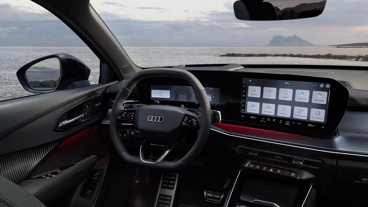 Blick von hinten auf das Cockpit des Q3 Sportback mit Lenkrad, Panoramadisplay und rotem Ambiente-Lichtpaket. Durch die Frontscheibe ist das Meer zu sehen.