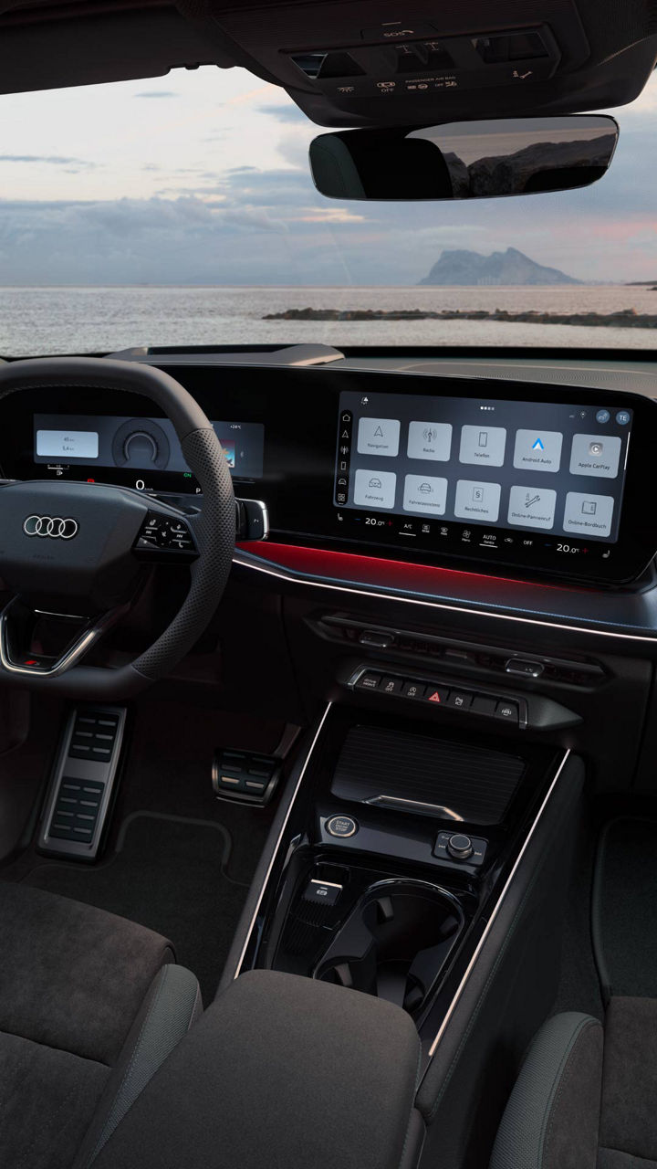 Blick von hinten auf das Cockpit des Q3 Sportback mit Lenkrad, Panoramadisplay und rotem Ambiente-Lichtpaket. Durch die Frontscheibe ist das Meer zu sehen.