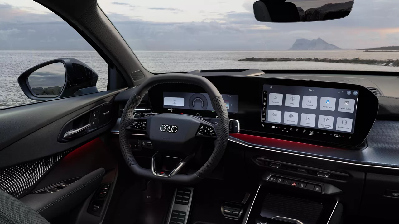 Rear view of the cockpit of the Q3 Sportback with steering wheel, panoramic display, and red ambient lighting package. The sea can be seen through the windshield.
