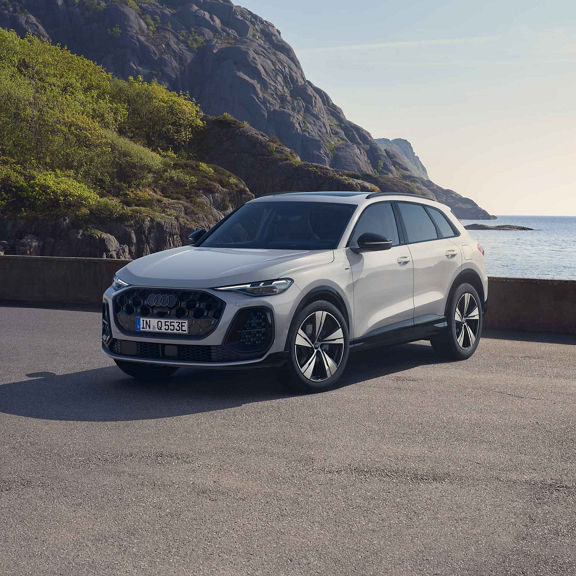 Audi Q5 SUV e-hybrid side front view in a parking lot in front of a bay