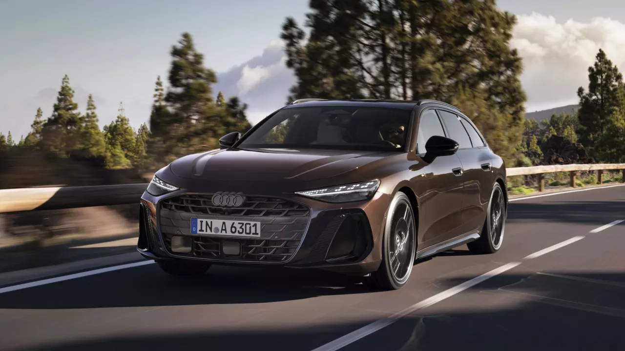 Ein Audi A6 Avant fährt durch eine Landschaft aus Bäumen und Hügeln. 