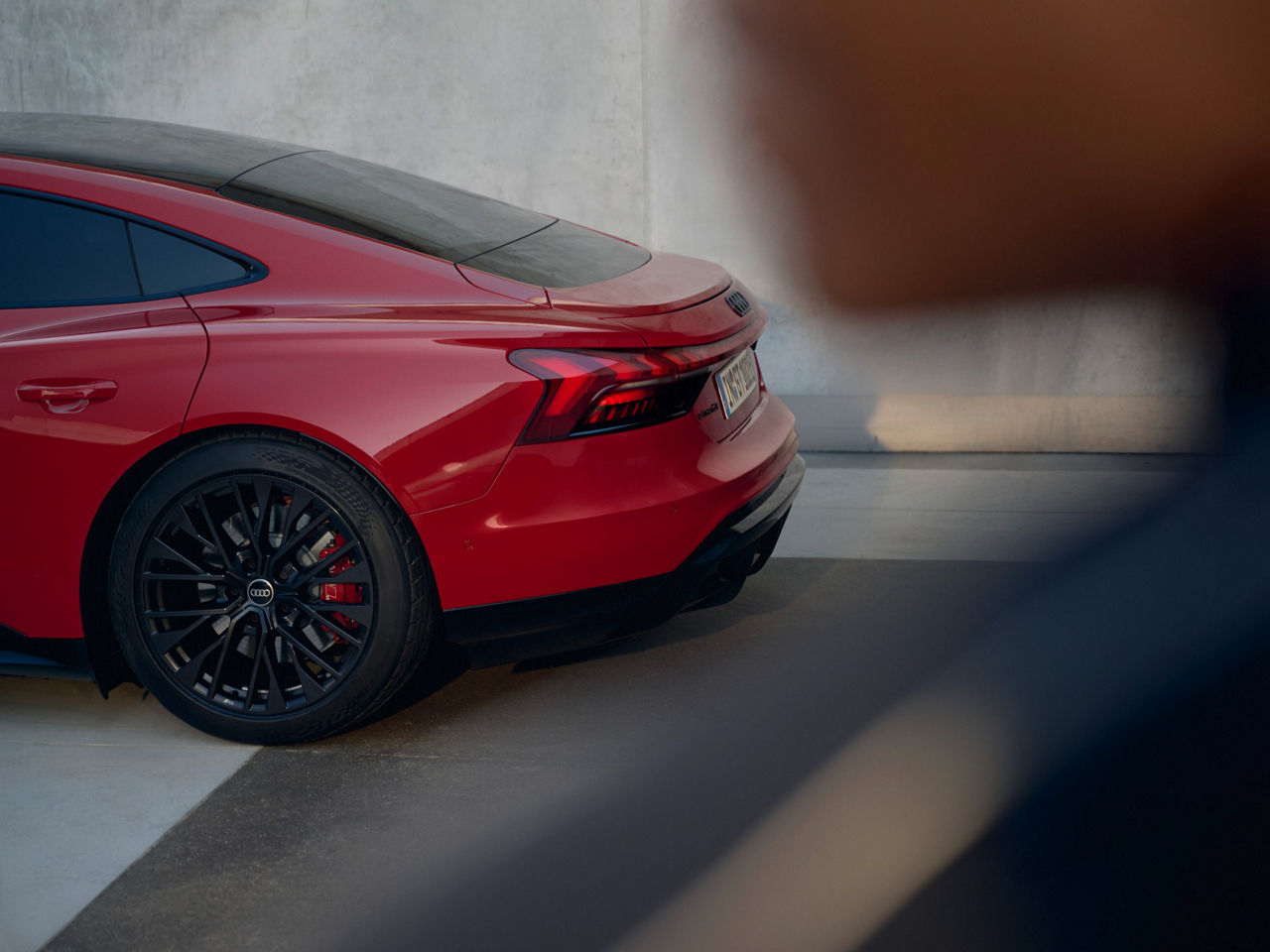 Ein Audi e-tron GT quattro steht geparkt vor einer Wand. Man sieht nur das hintere Drittel des Fahrzeugs.