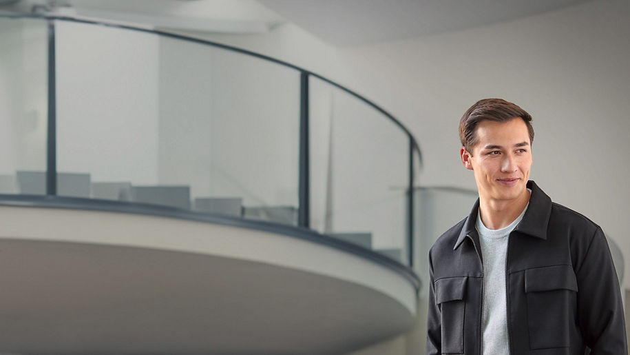 A young man with dark hair stands in a stairwell and looks to the side