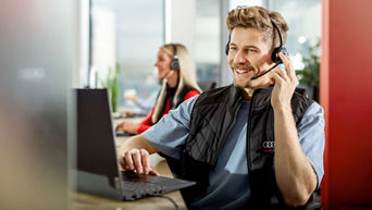 Young, colored woman with a headset sits at her desk and types something on the keyboard