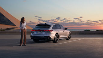 Frau im Businesslook steht neben einem silbernen Audi A5 Avant