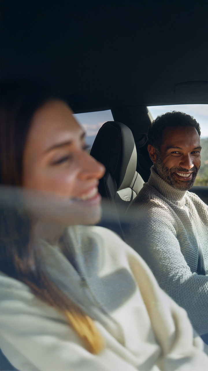 Mann und Frau sitzen im Auto und lachen