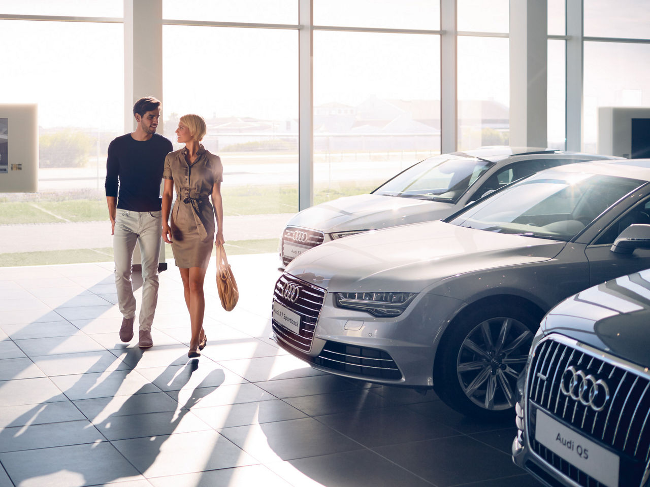 Mann und Frau gehen in einem Autohaus auf die Kamera zu und schauen sich an