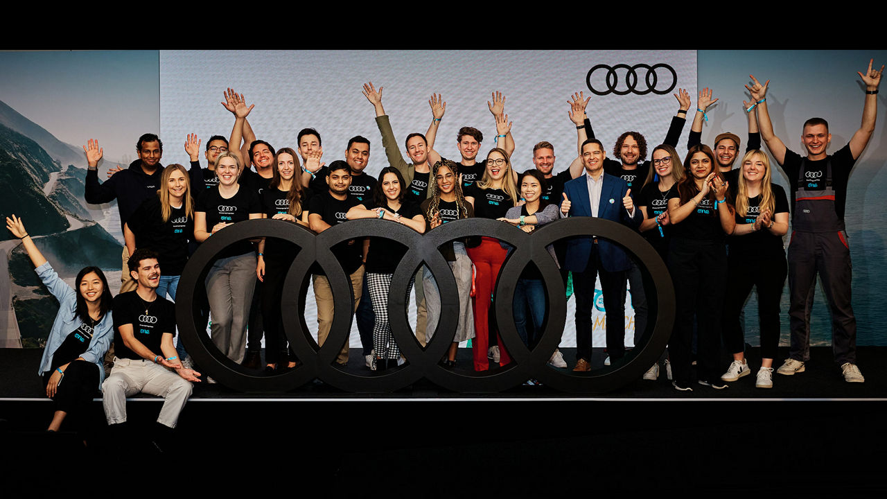 Group of joyfully cheering young people on the stage of an Audi event