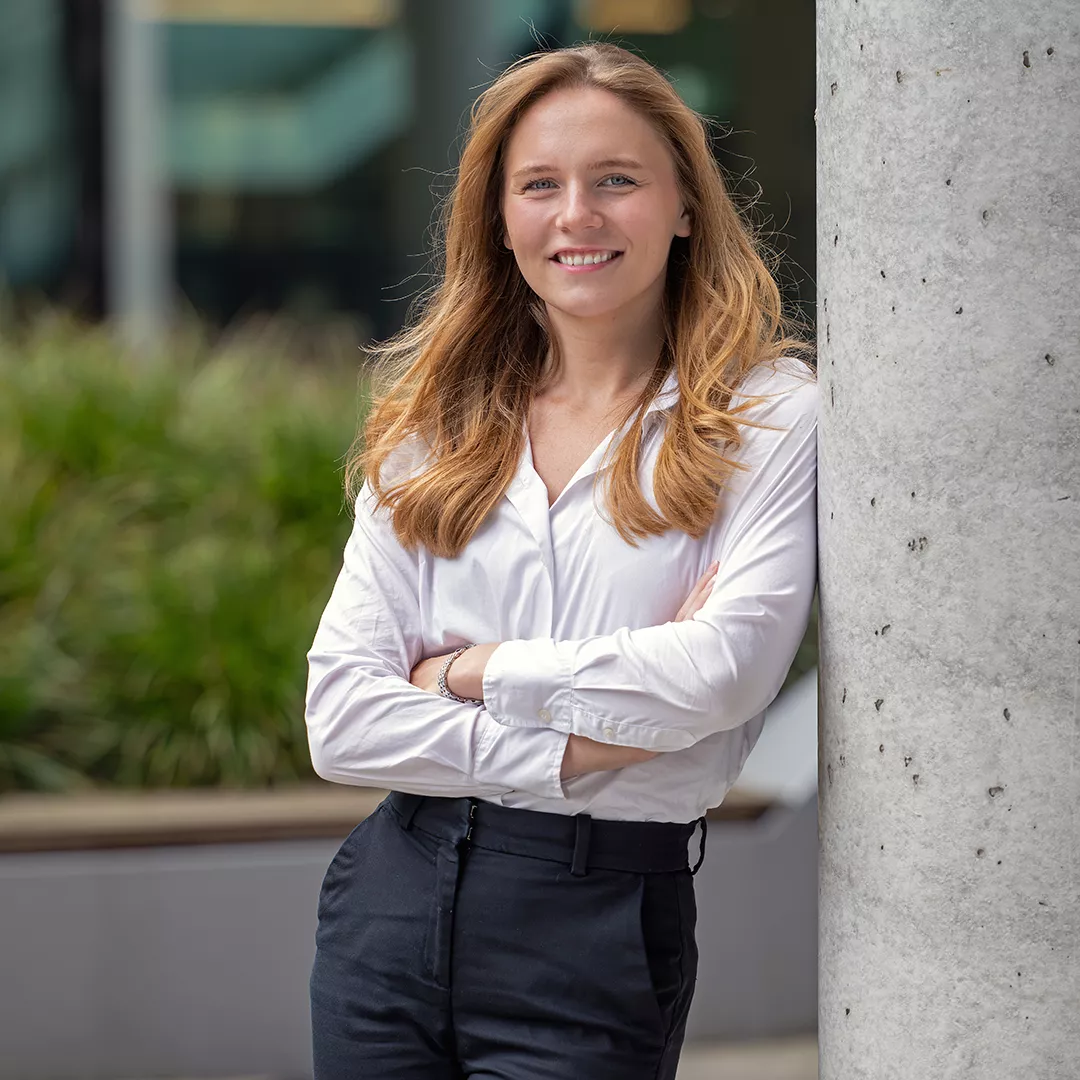 Elisabeth Lohner stands against a wall with her arms crossed and smiles at the camera