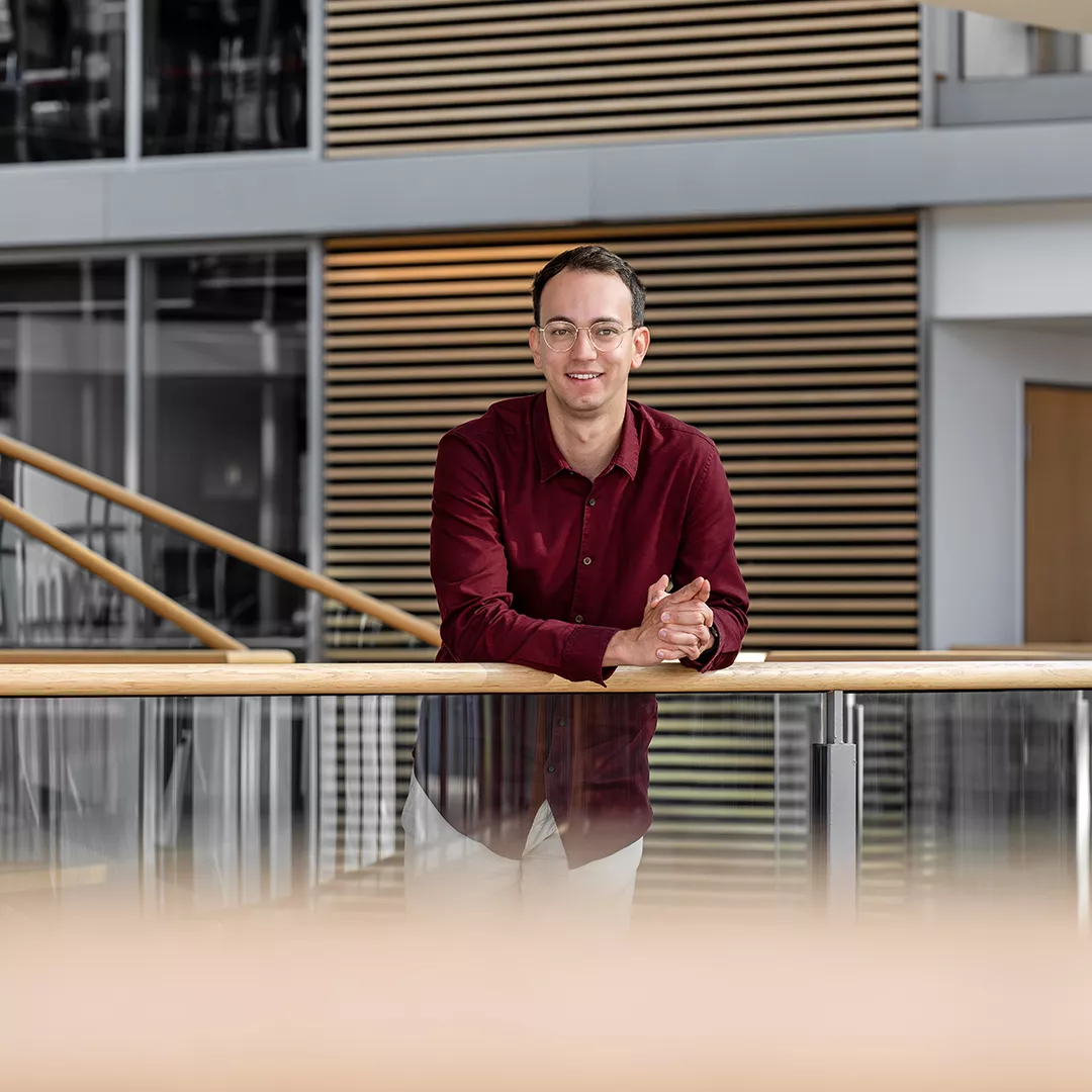 Hannes Langer stands at a railing and laughs at the camera