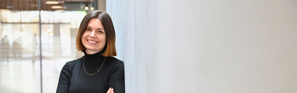 Lisa, Product Designer SDC, smiles at the camera and leans against a wall