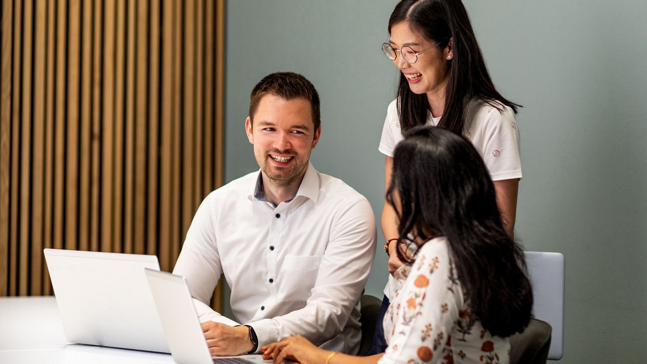 Three young people in fron of a Laptop, smiling