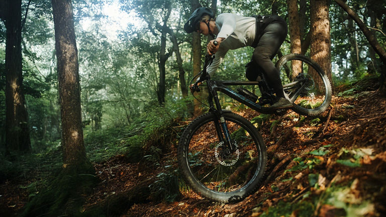 Lissi Lanz rides her mountain bike down a mountain through a forest