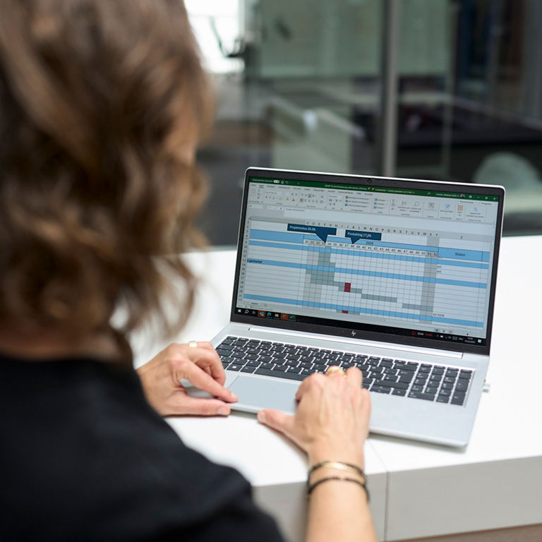 Man sieht Melanie Limmer von hinten und sie schaut sich etwas auf dem Laptop an