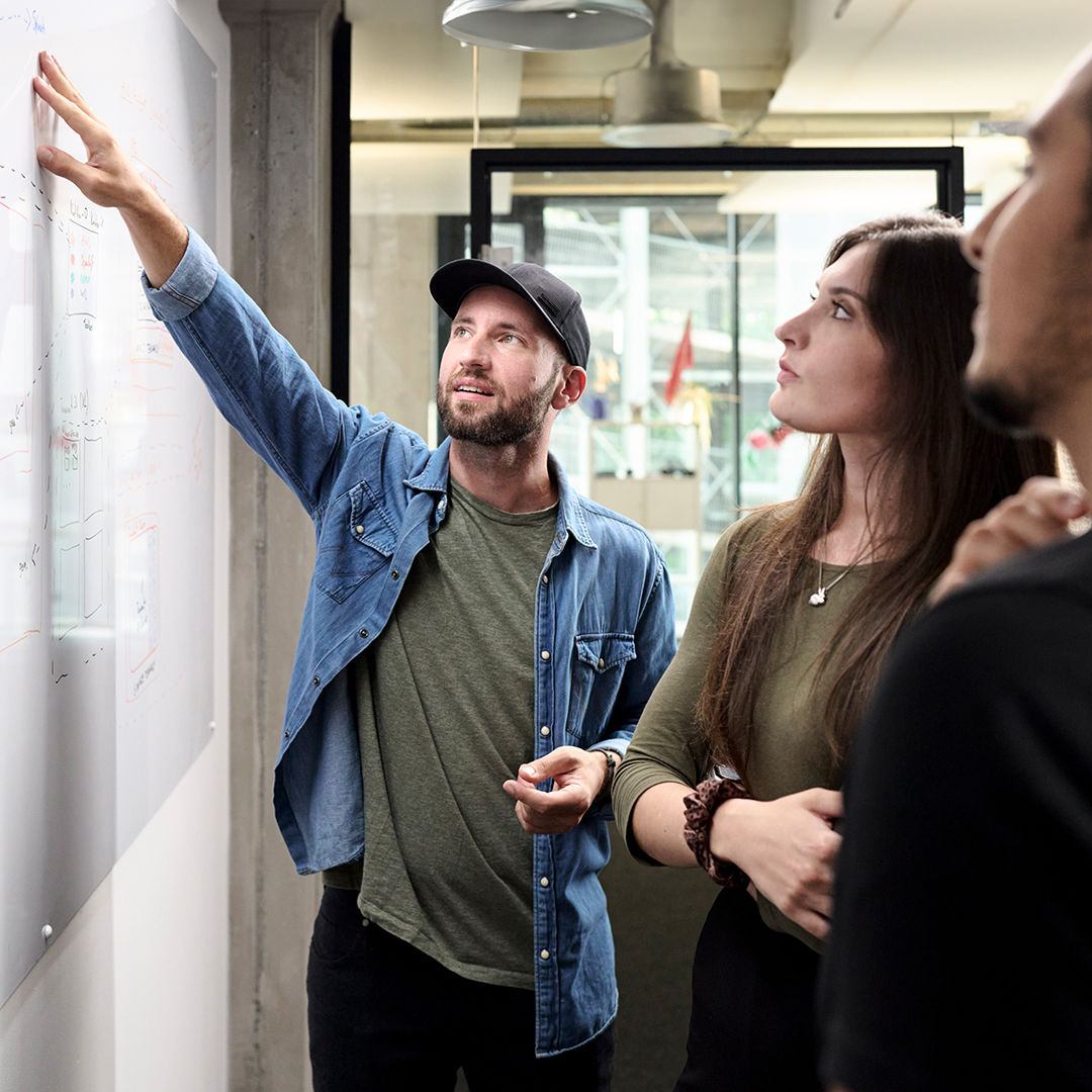 Sebastian Kister shows his colleagues something on a whiteboard.